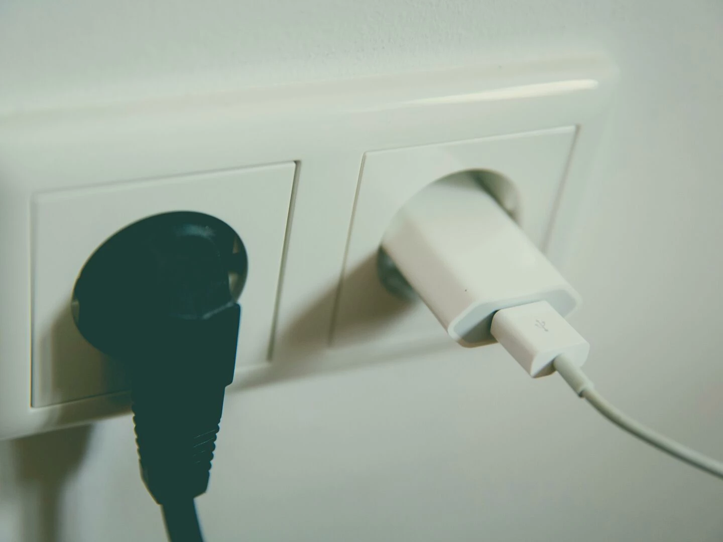 a closeup view of a wall outlet with two plugs inserted capturing the simplicity of electrical connectivity