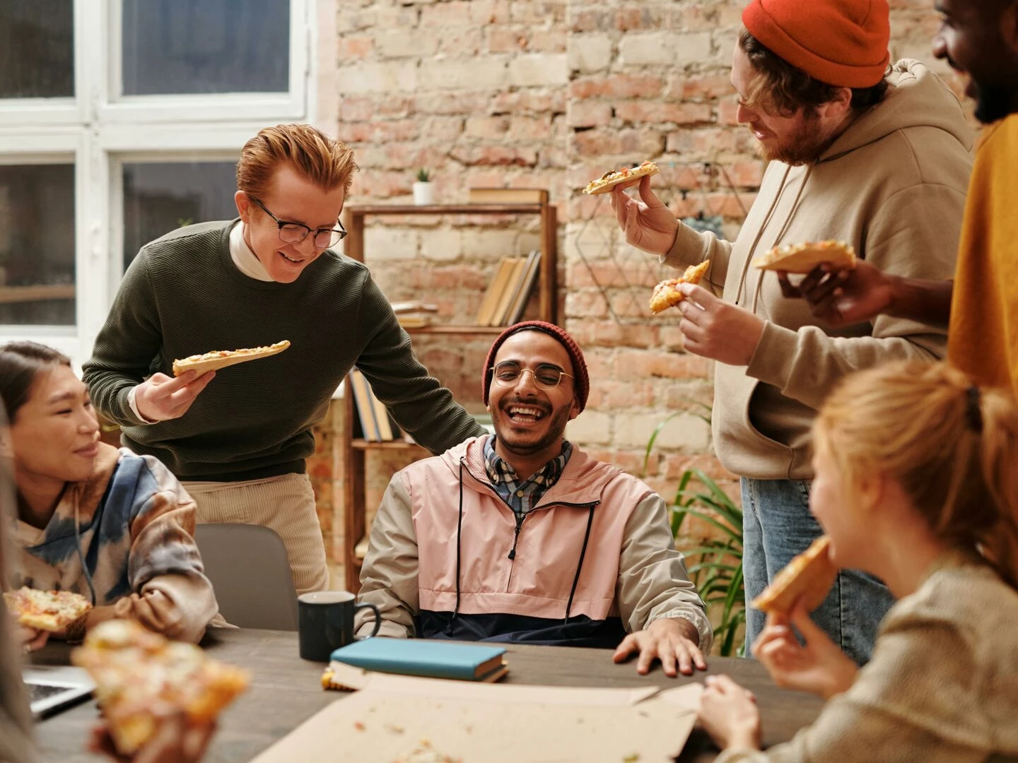 a joyful group of diverse friends enjoying pizza together in a cozy indoor setting