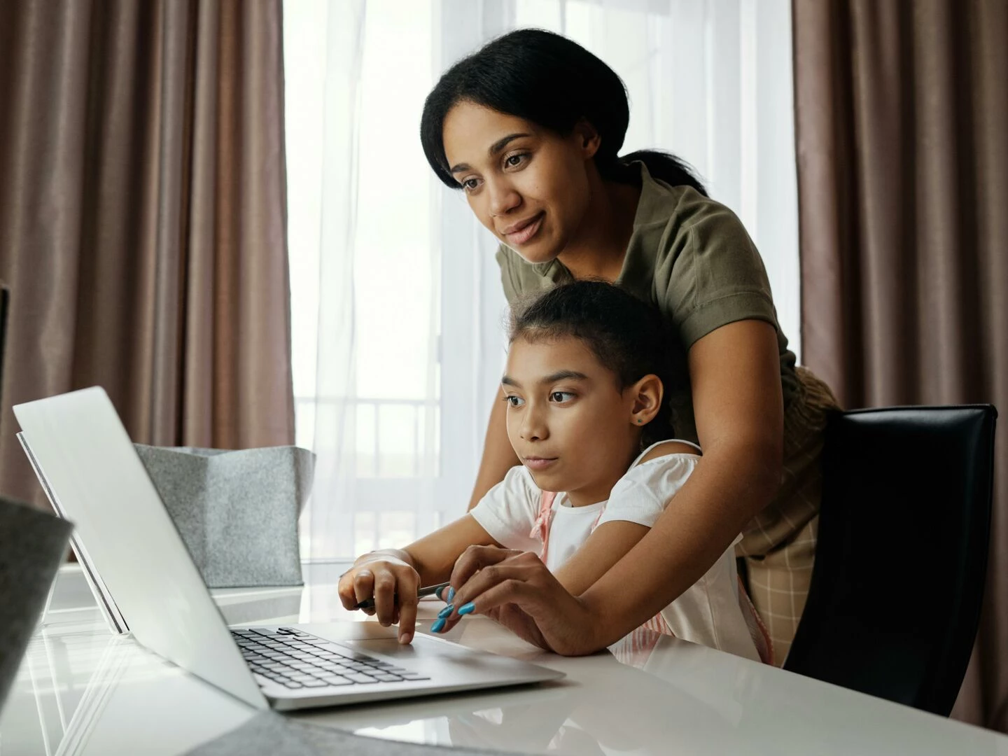 a mother helps her daughter with an online lesson on a laptop showcasing family bonding and education at home