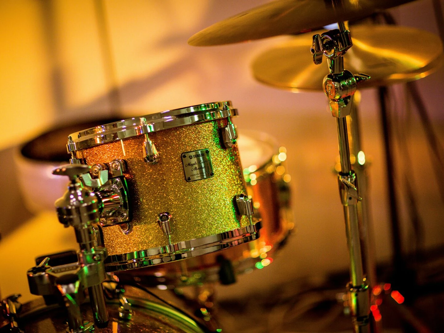 a vibrant closeup photo of a glittery drum set under concert lights evoking a lively music performance