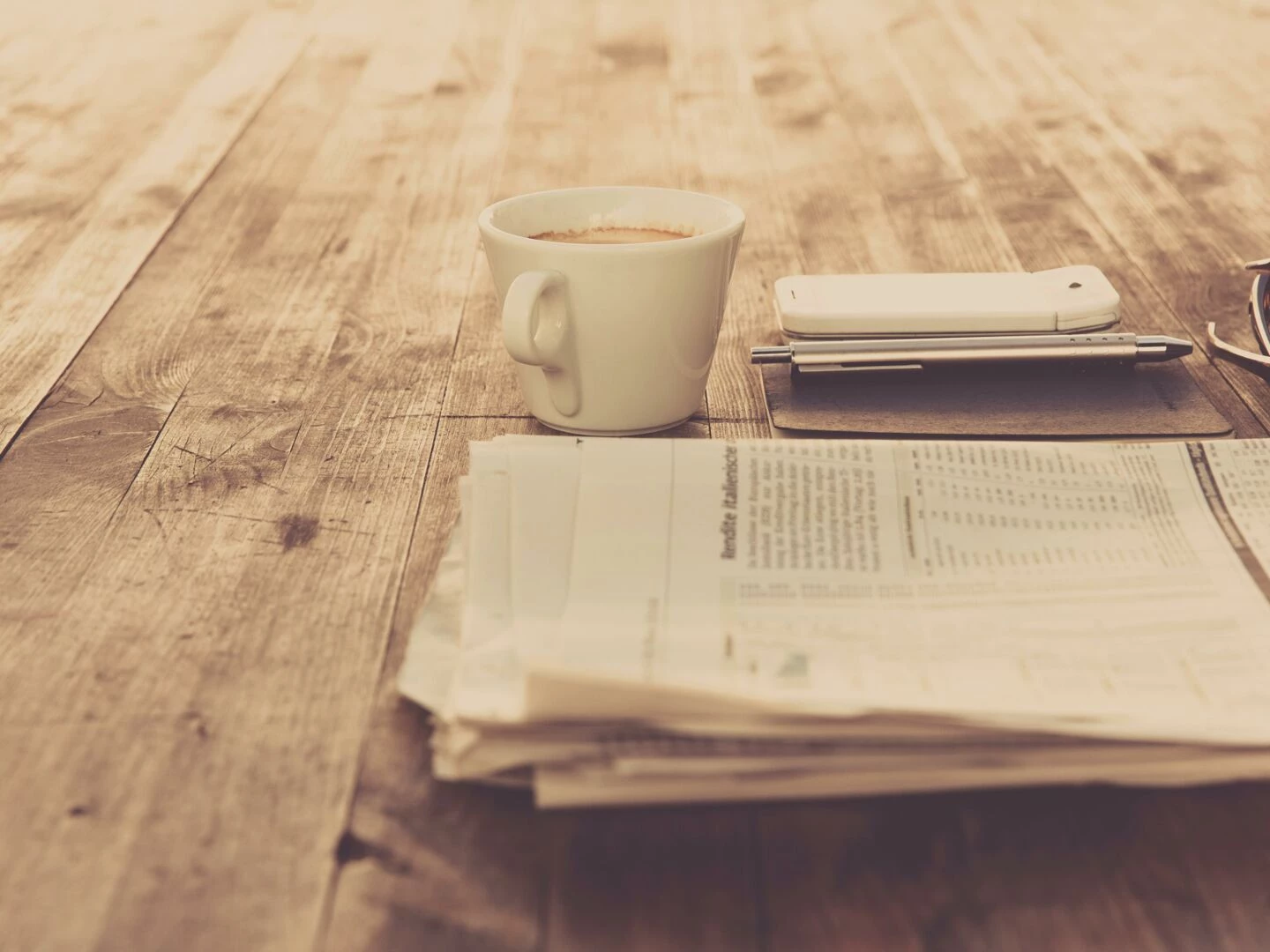 a warm vintage morning setup with coffee newspaper and smartphone on wooden table