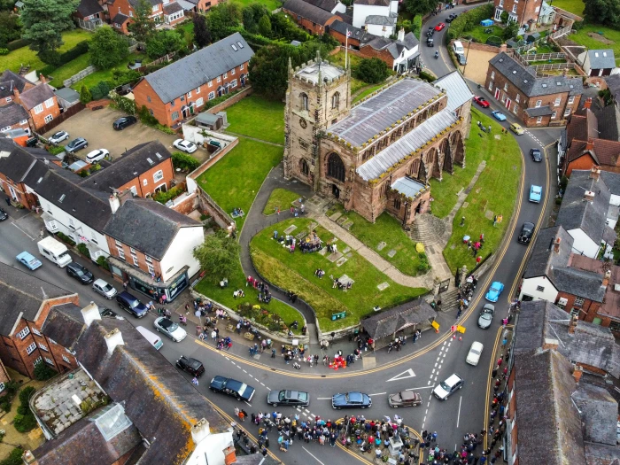 aerial view of vehicle parade passing st james 39  church in audlem