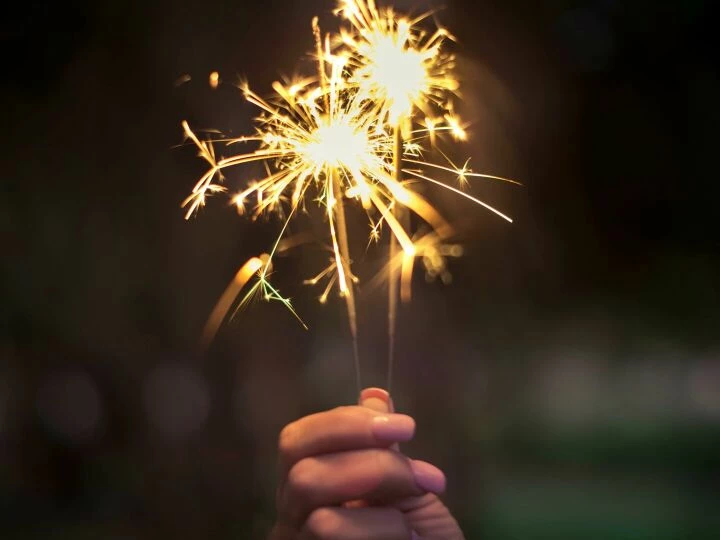 A hand holding sparklers glowing brightly in a dark night, capturing the essence of celebration.