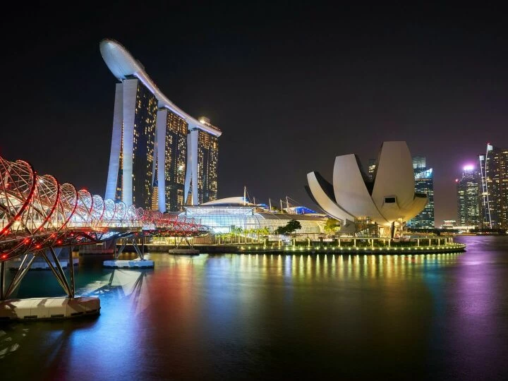 Stunning night view of Marina Bay Sands and Helix Bridge illuminated over water in Singapore.