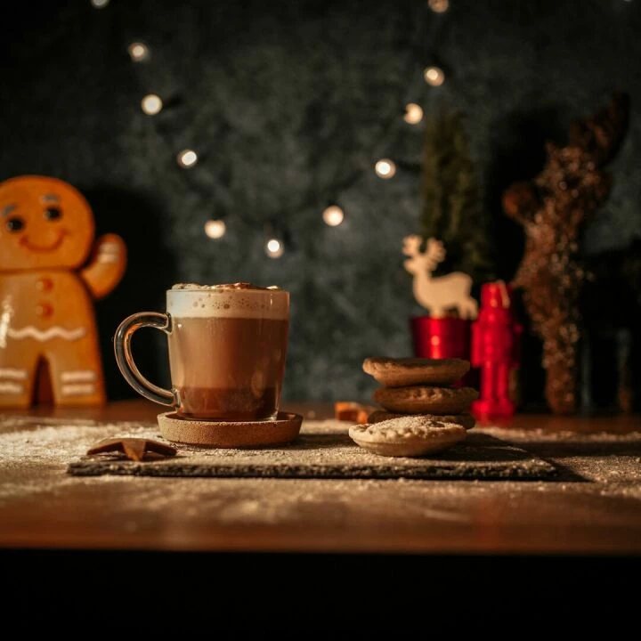 Warm Christmas scene featuring hot chocolate, mince pies, and a gingerbread man with festive lights.