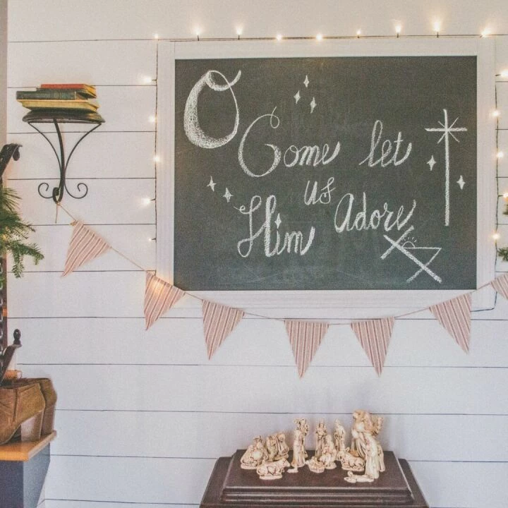 Festive Christmas setup featuring a chalkboard with holiday message, wreath, and nativity scene.