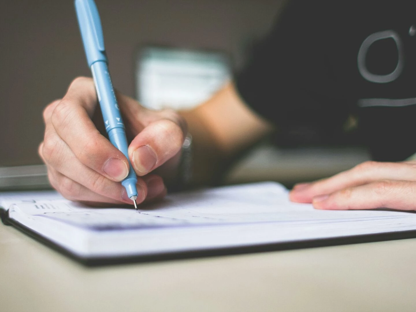 closeup of hand writing in notebook using a blue pen focus on creativity
