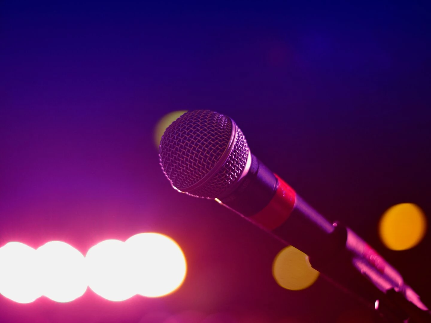 colorful stage lighting highlights a microphone in a closeup view perfect for music and performance themes