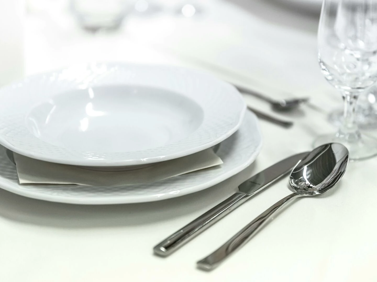 elegant dining table with white porcelain plates and silver cutlery elegantly arranged