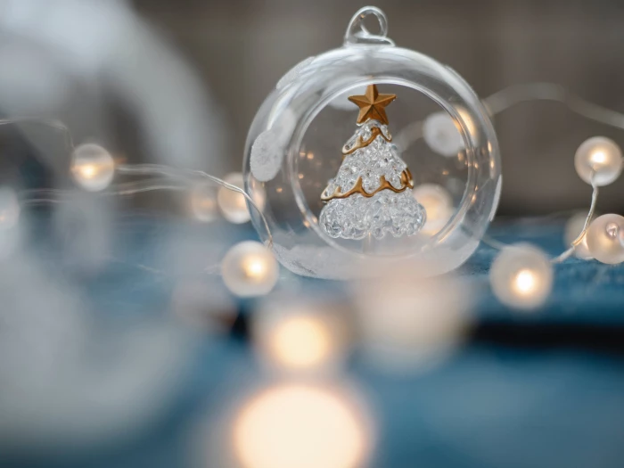 glass christmas tree inside transparent ball surrounded by burning garland for festive decorations