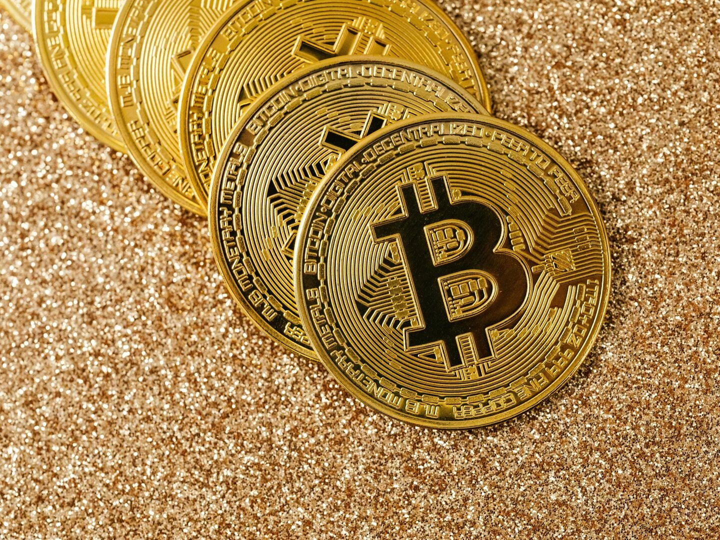 golden bitcoin coins arranged on a sparkling glitter surface symbolizing cryptocurrency and wealth