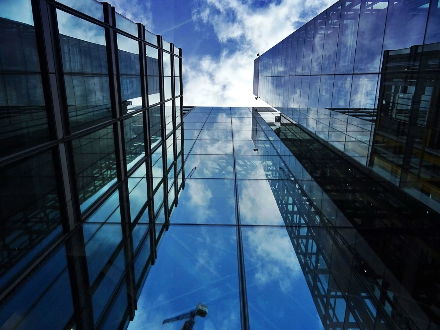 perspective view of modern skyscraper facades with glass reflections of clouds and sky