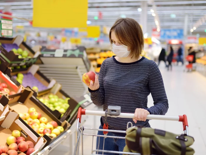 young woman wearing disposable medical mask shopping in supermarket during coronavirus pneumonia outbreak